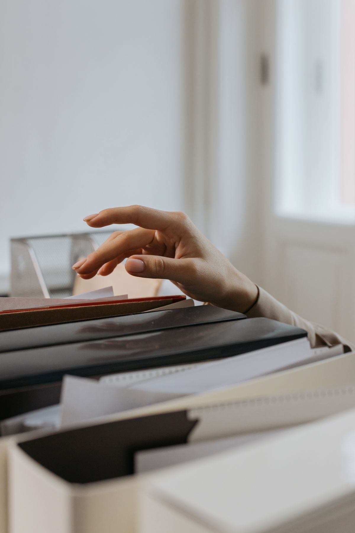 Hand reaching into a row of document folders, the paperwork such as receipts, registration and water tests that a water softener warranty claim depends on