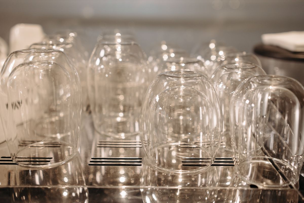 Drinking glasses drying upside down on a stainless steel rack after a dishwasher cycle