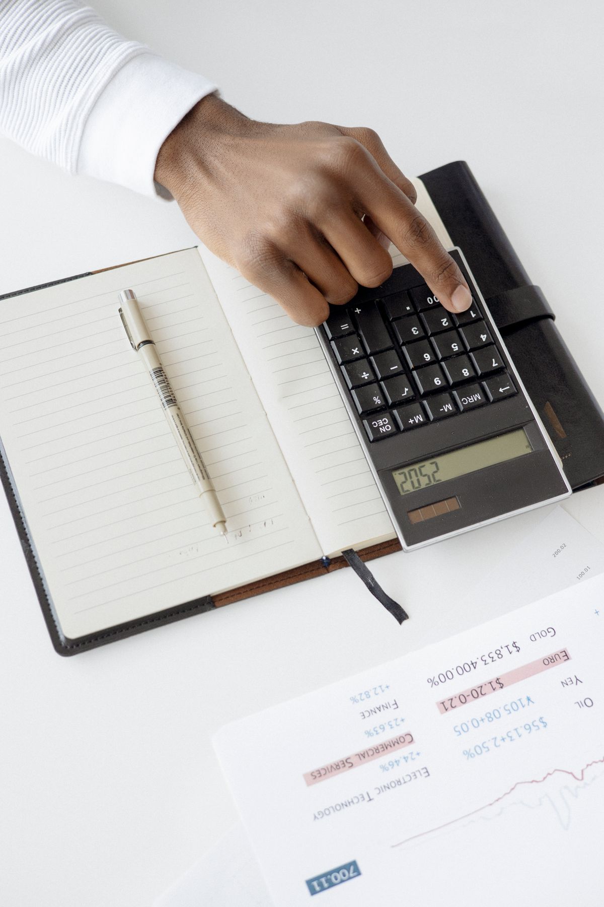 Hand pressing keys on a black calculator beside an open notebook, working out whether a water softener is too large for a household's daily hardness load