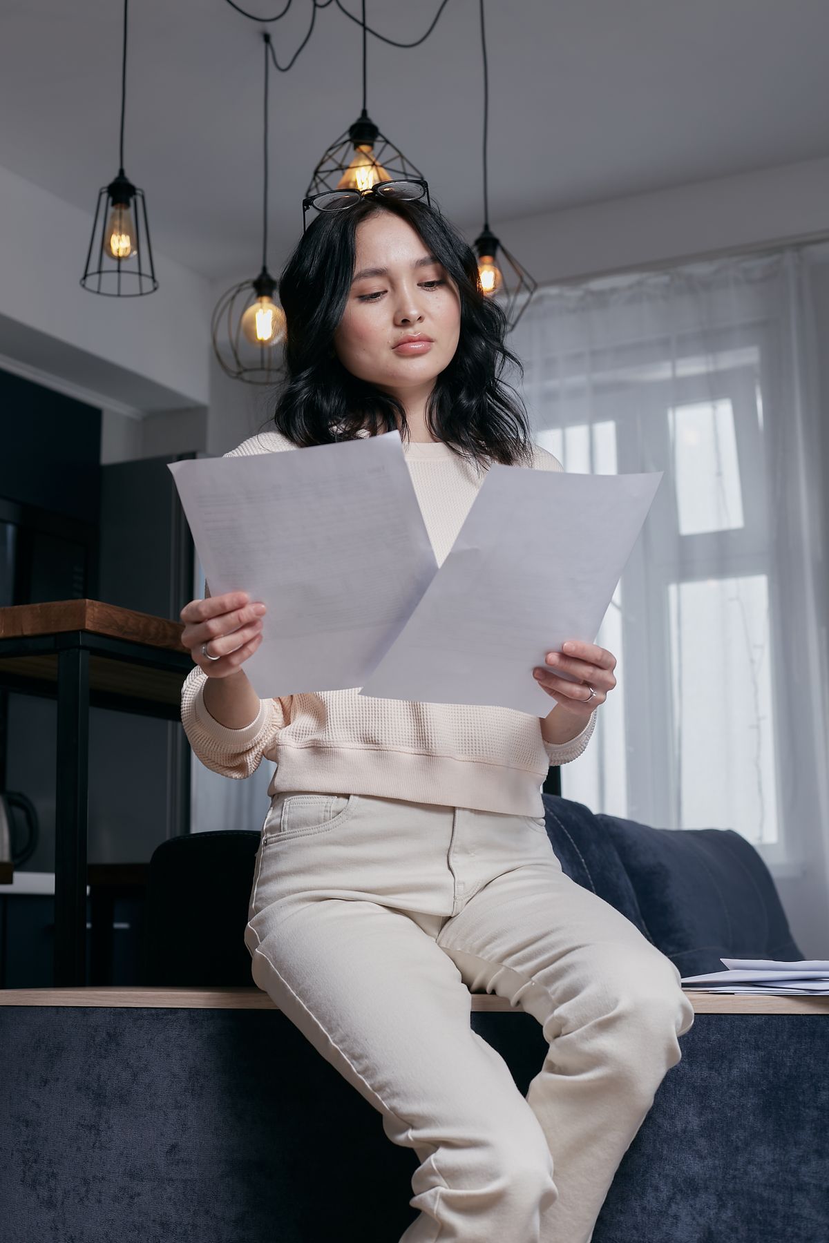 Woman at home reading two printed pages closely, the way a homeowner works through a water hardness report