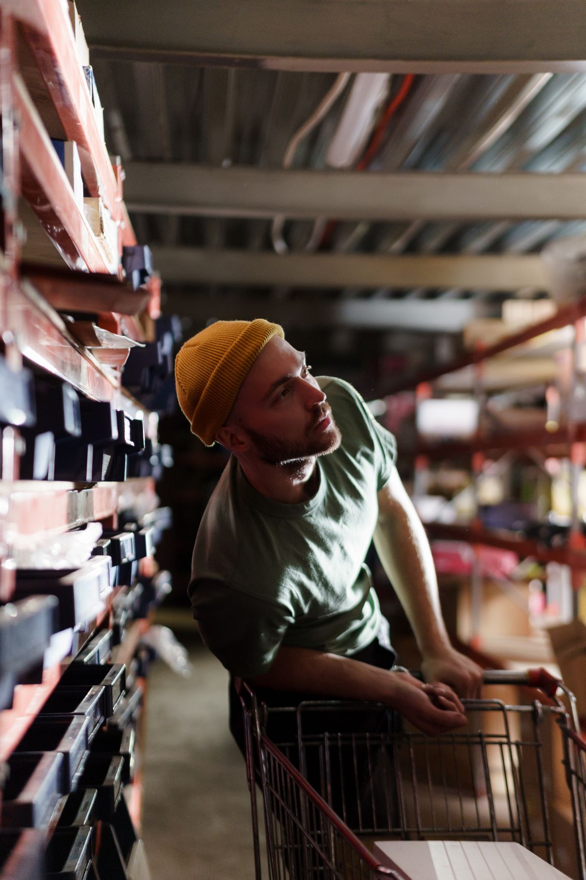Shopper with a cart reading the labels on a long run of warehouse shelves, comparing products the way a budget water softener buyer compares boxes