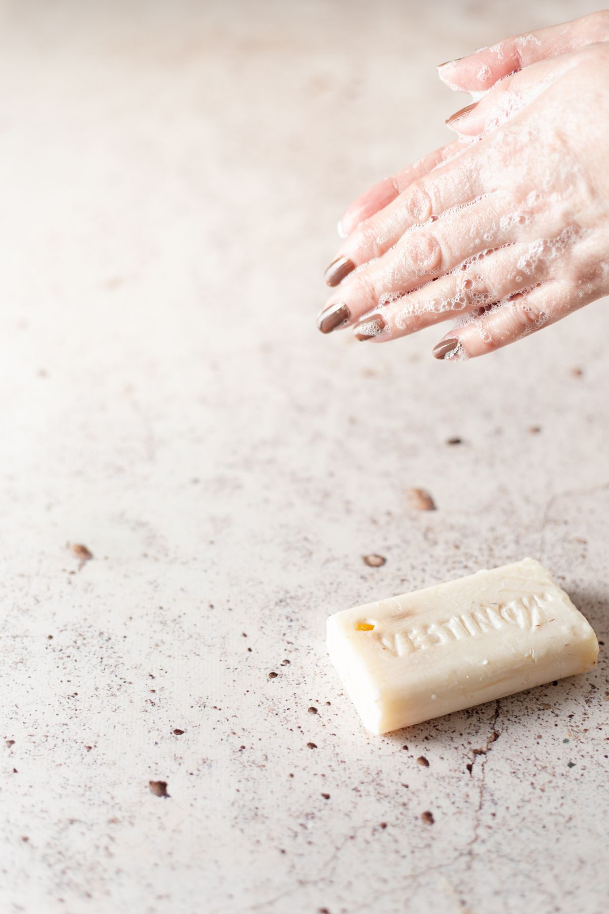 Hands lathered with soap showing dense foam, the lather soft water produces from a fraction of the usual product