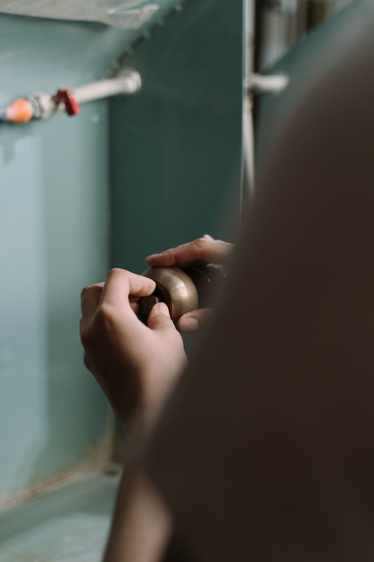 Hands working on pipework under a kitchen sink during a plumbing check