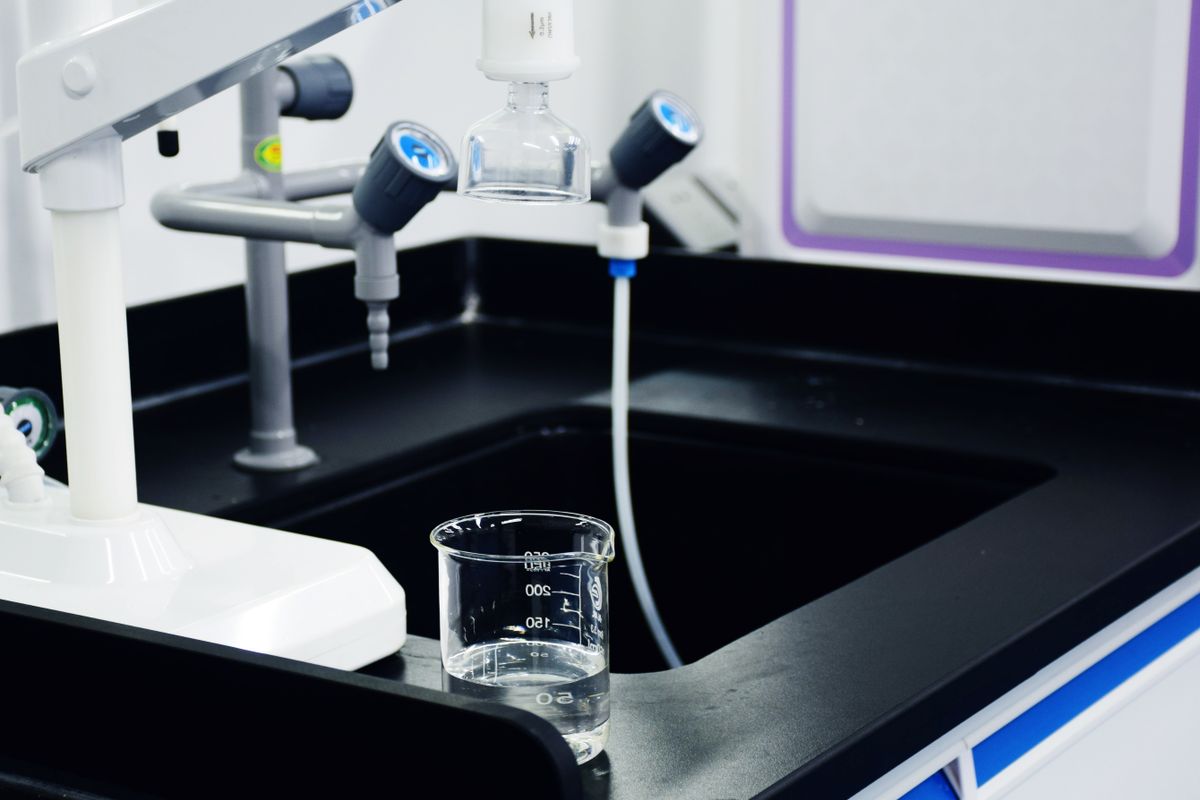Laboratory water filtration apparatus with beakers and taps, representing the oxidation and filtration options for hydrogen sulfide removal