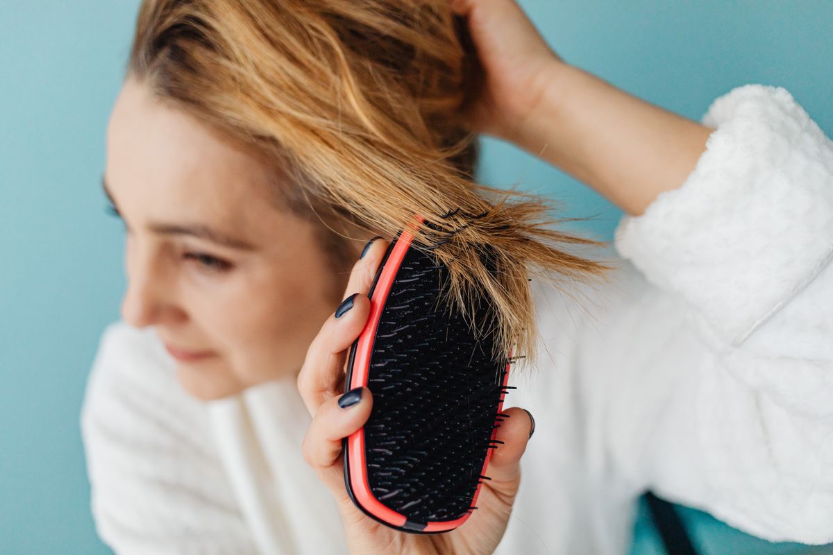Close-up of a woman brushing long hair, checking texture and drag after washing