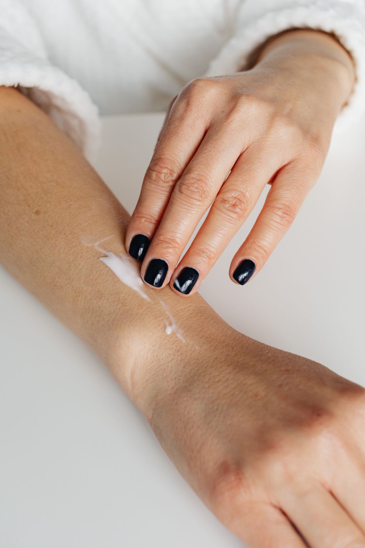 Person applying moisturising cream to a forearm, the routine that continues for many people with dry skin after a water softener