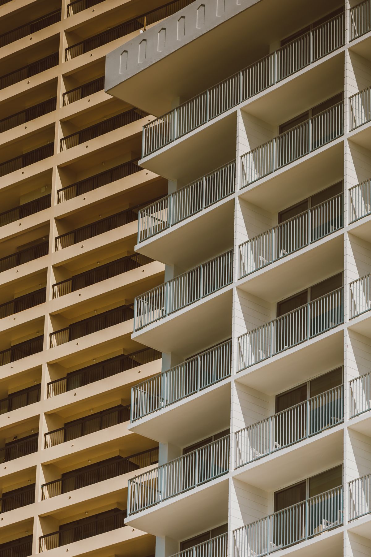 Stacked balconies with white railings on a high-rise residential condominium building, one unit above another