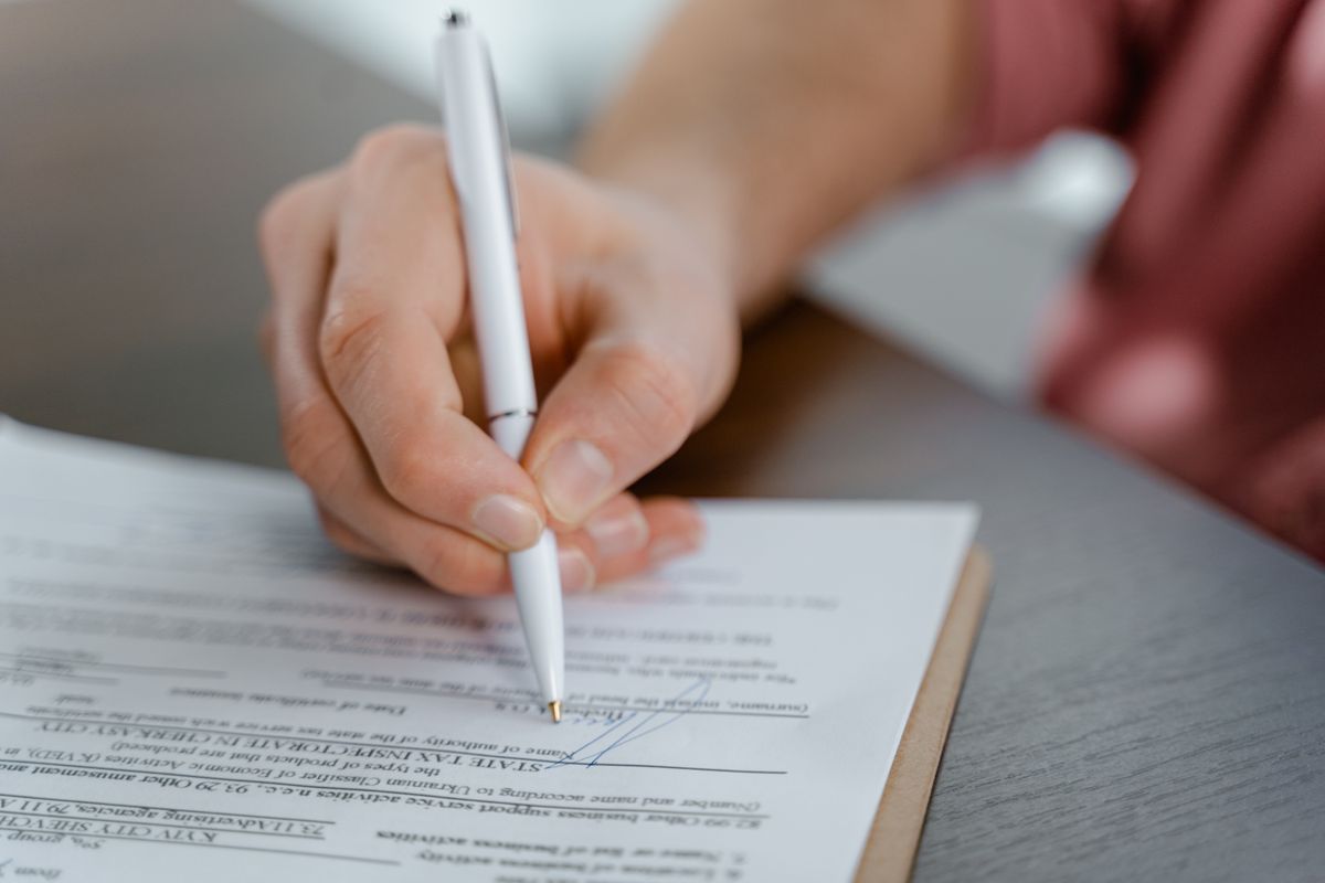 Hand signing an official document with a ballpoint pen, the in-home dealer contract that starts the three-day cooling-off period for a water softener sale