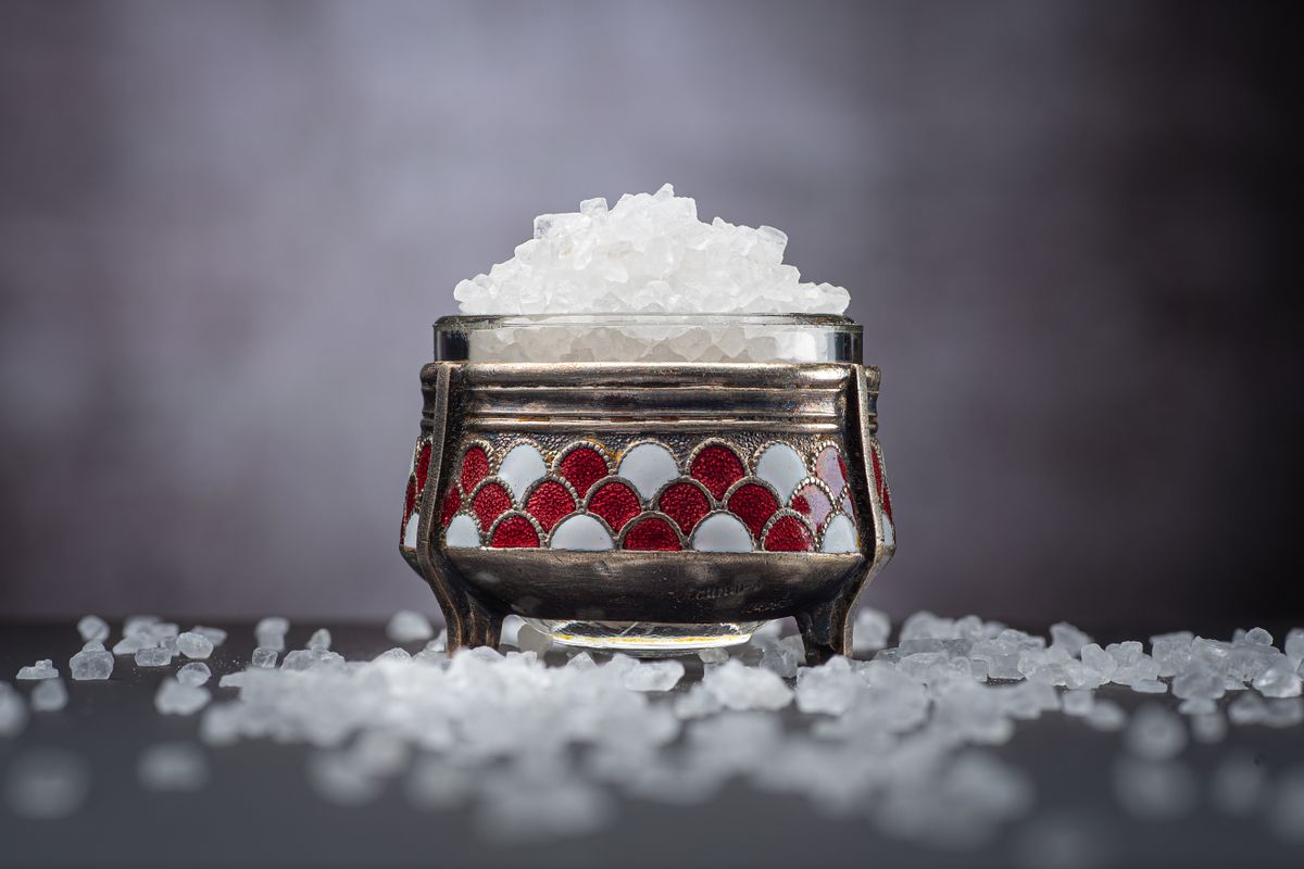 Coarse white salt crystals heaped in a small metal cellar, the sodium chloride that is dissolved into brine to regenerate a water softener