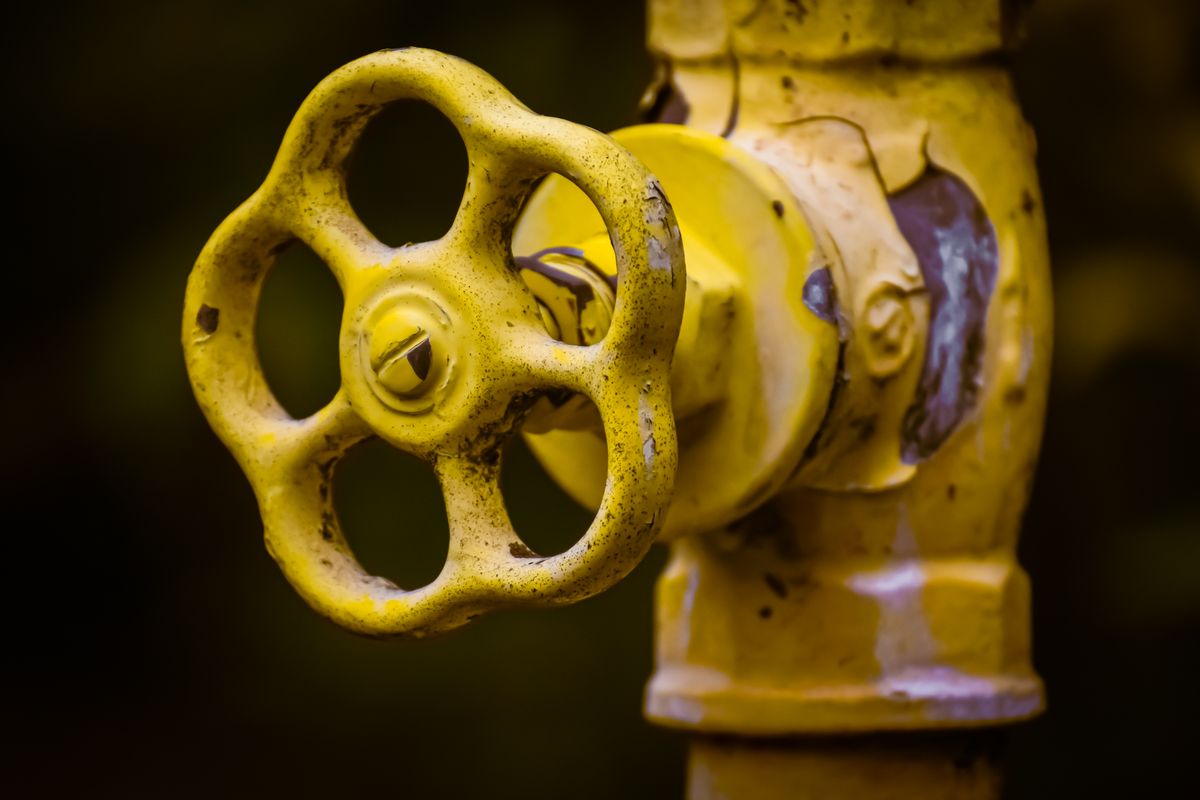 Close-up of a rusty yellow shut-off valve on a pipe, the kind of quarter-turn valve that restricts flow badly when left partly closed after a softener install