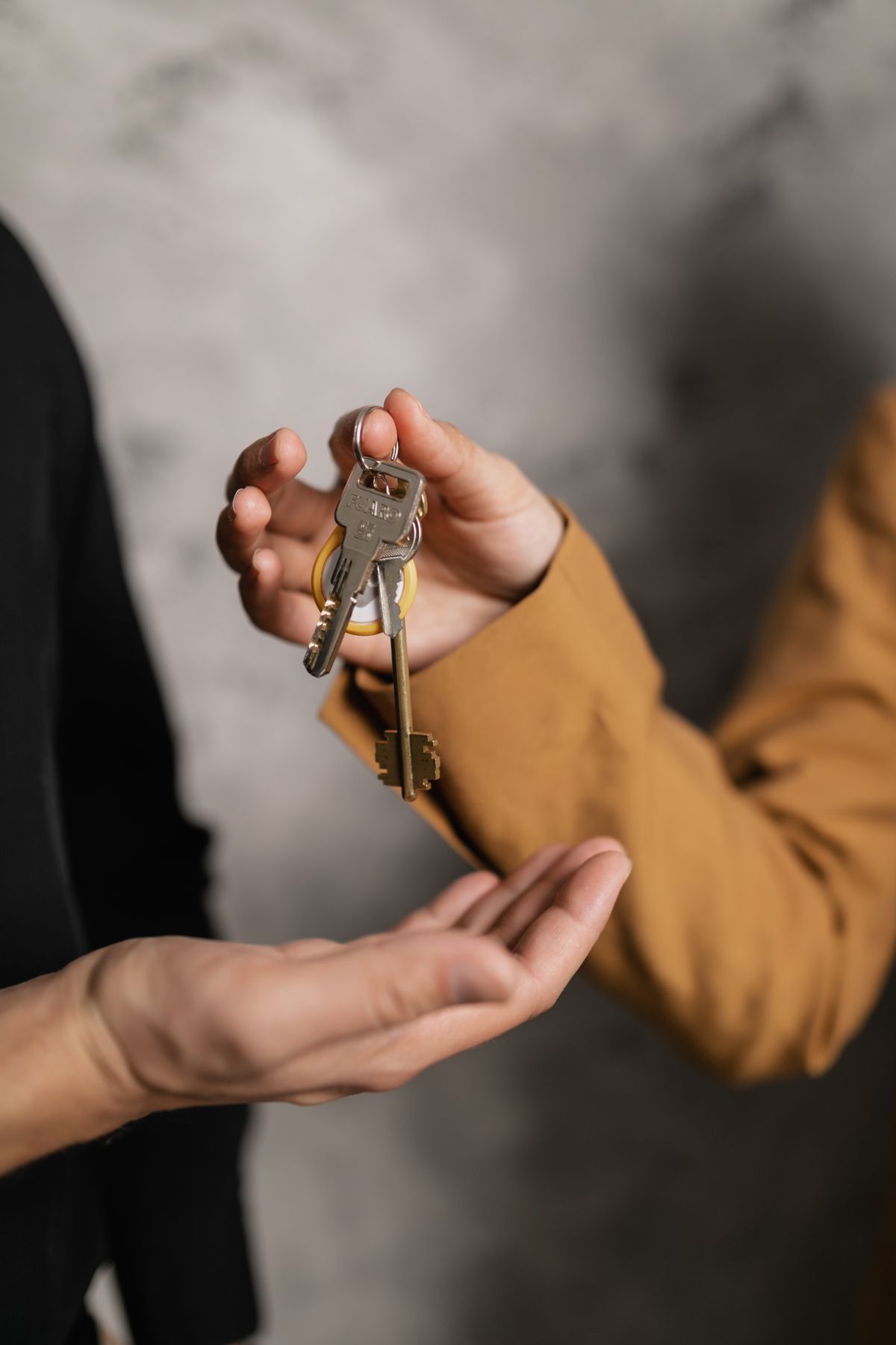Two hands passing a set of house keys from one person to another at the end of a tenancy