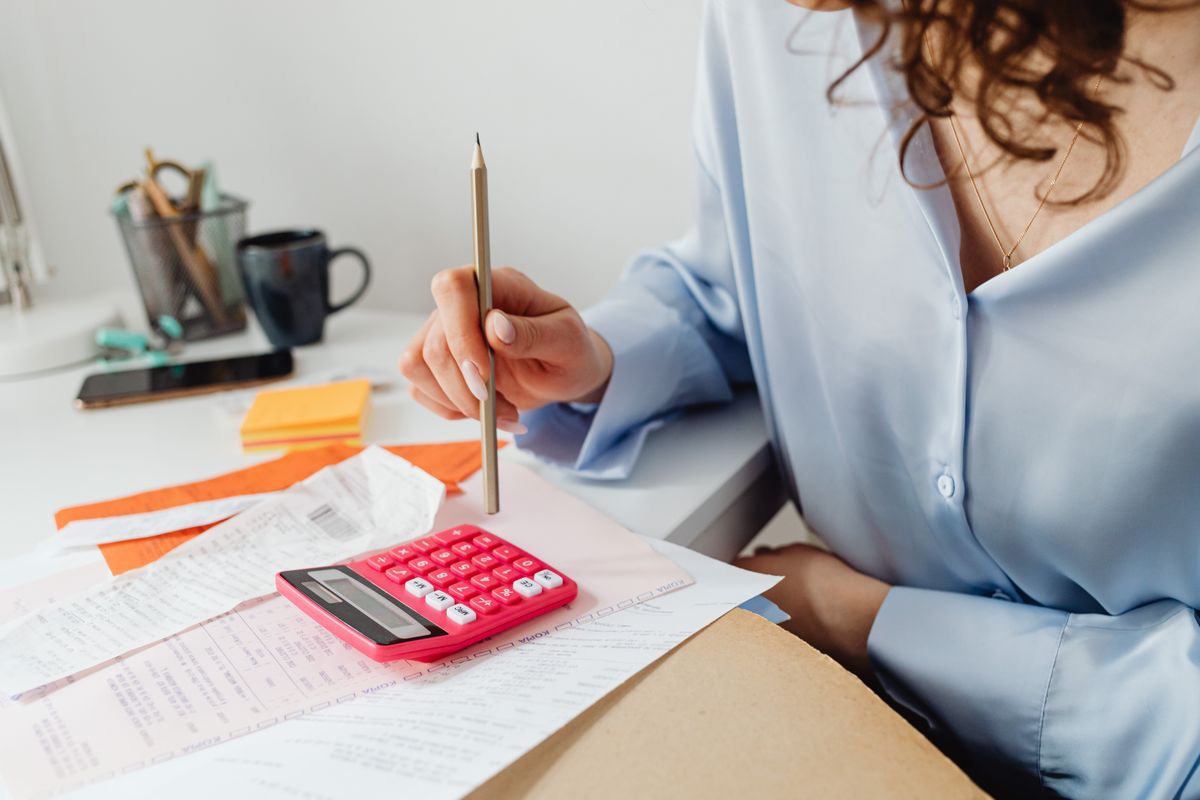 Woman working through household bills with a pencil and calculator, the calculation that turns a softener drain flow rate into a monthly water and sewer cost