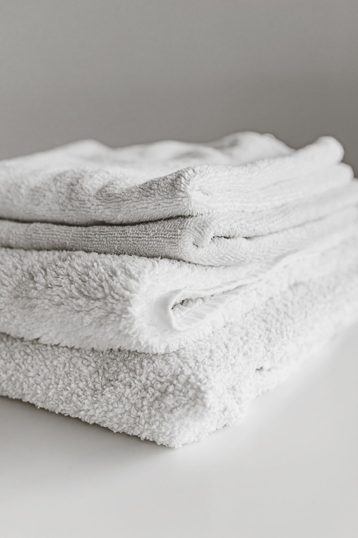 Stack of neatly folded clean white towels, the opposite of laundry stiff after washing in hard water