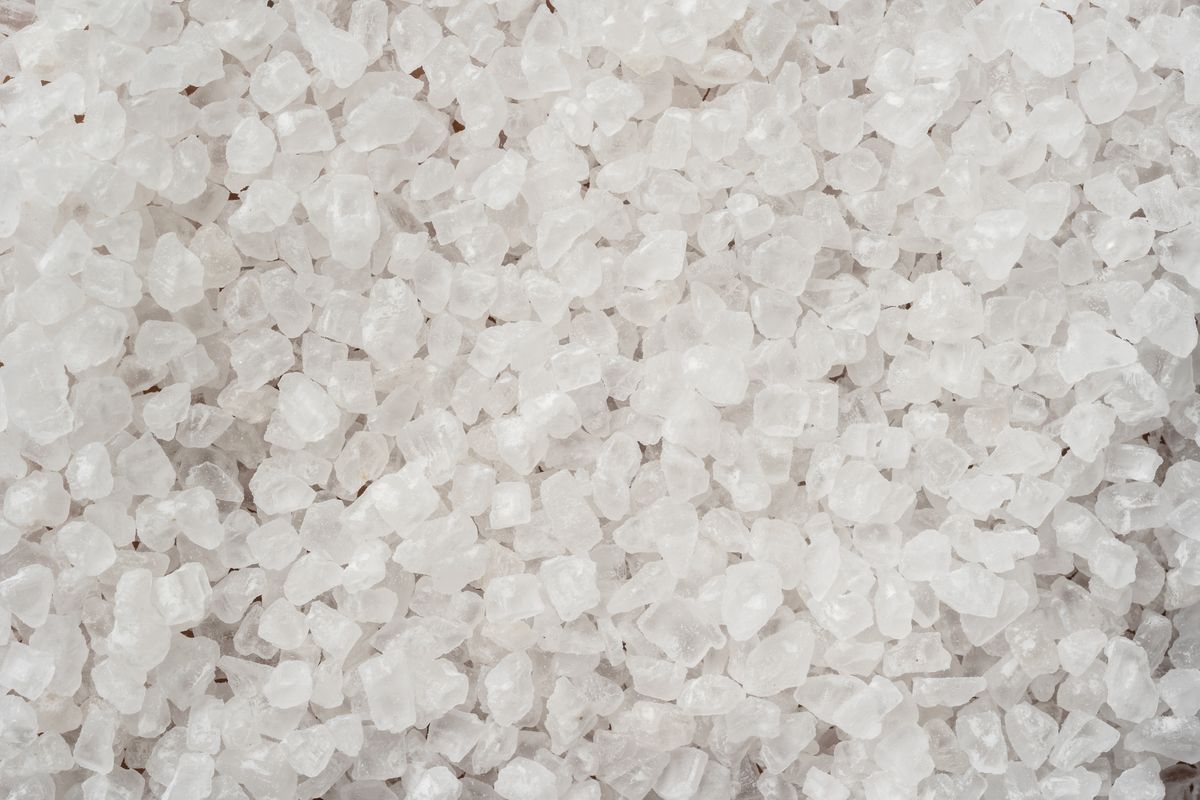 Coarse white sea salt crystals, the material a softener uses for regeneration and flushes to drain rather than into the household supply