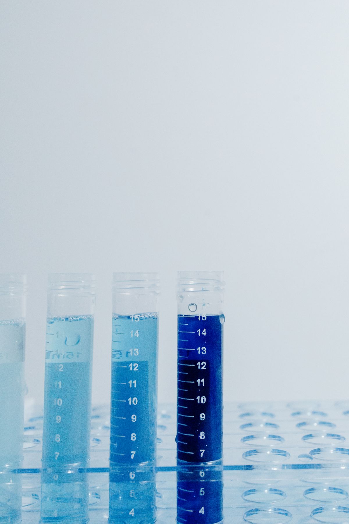 Graduated test tubes of water samples in a lab rack, the pH, alkalinity and hardness tests that decide which acid neutralizer a well needs