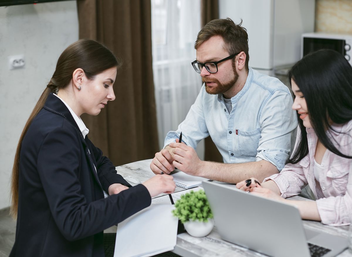 Dealer representative writing on paperwork at a home table while a couple reads along, the moment to check a Culligan vs EcoWater softener warranty clause by clause
