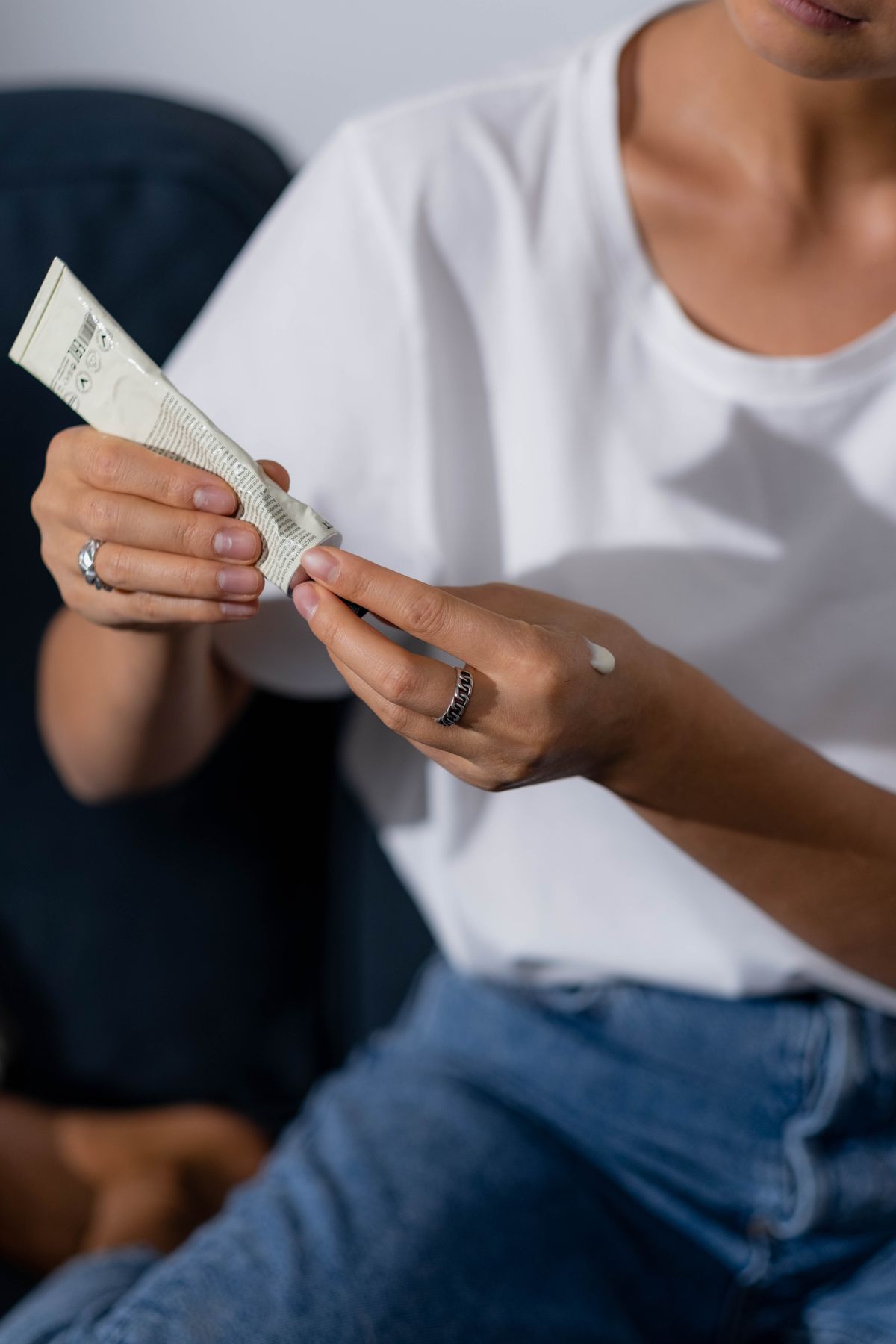 Woman applying hand lotion as part of a daily body-care routine, one variable among several behind persistent dryness