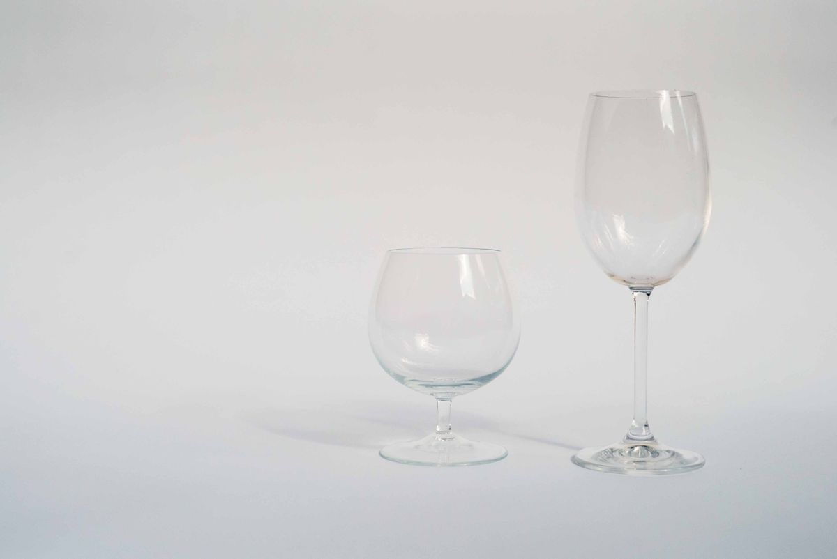 Two empty clear wine glasses on a white background showing the clarity cloudy glasses from a dishwasher lose