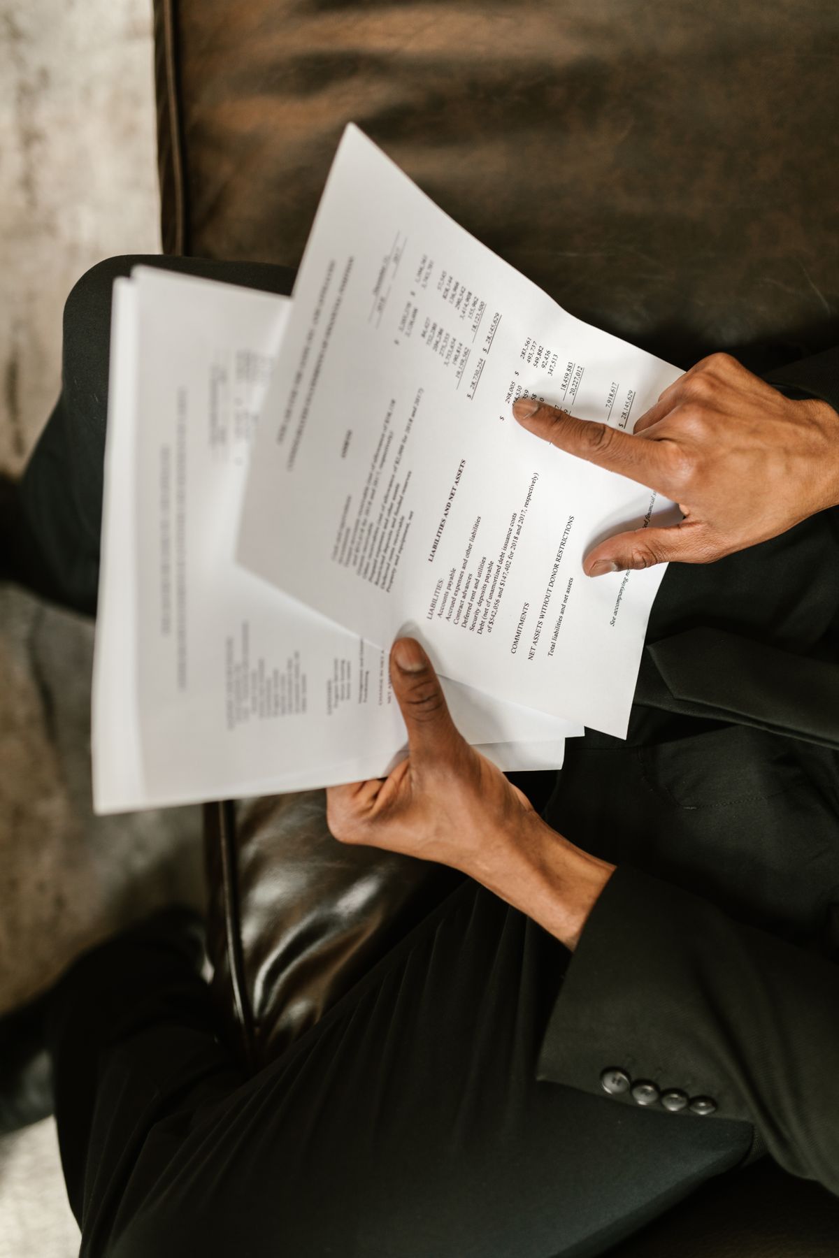 Homeowner holding two printed pages side by side and pointing at a line of figures, comparing the installation scope on two water softener quotes