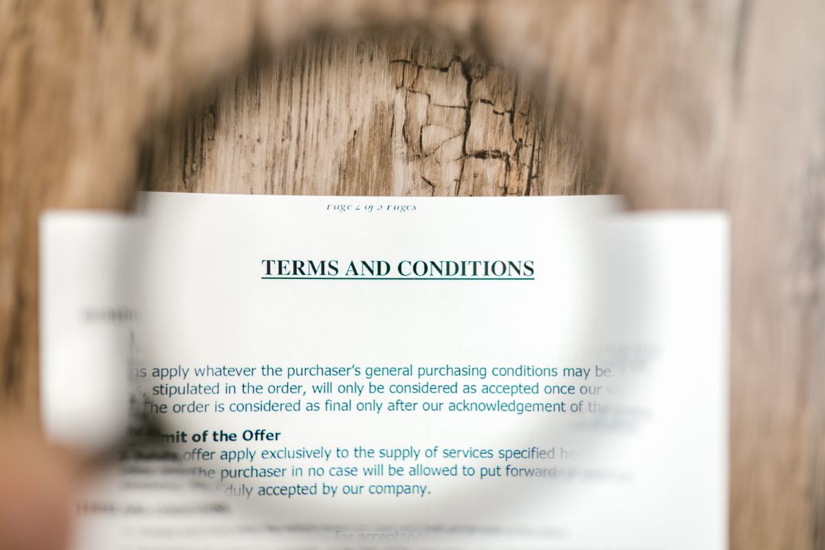 Magnifying glass held over a printed terms and conditions document, reading the fine print of a product warranty