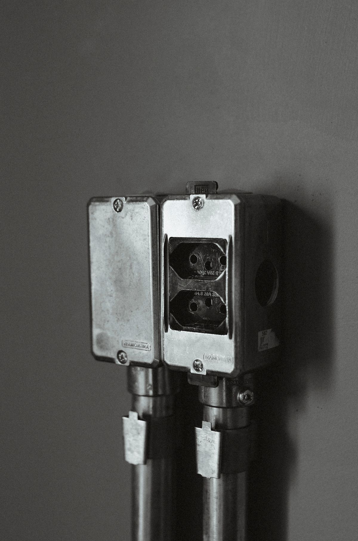 Two metal-clad electrical outlet boxes mounted on a wall and fed by steel conduit, providing power where an electric water softener could plug in