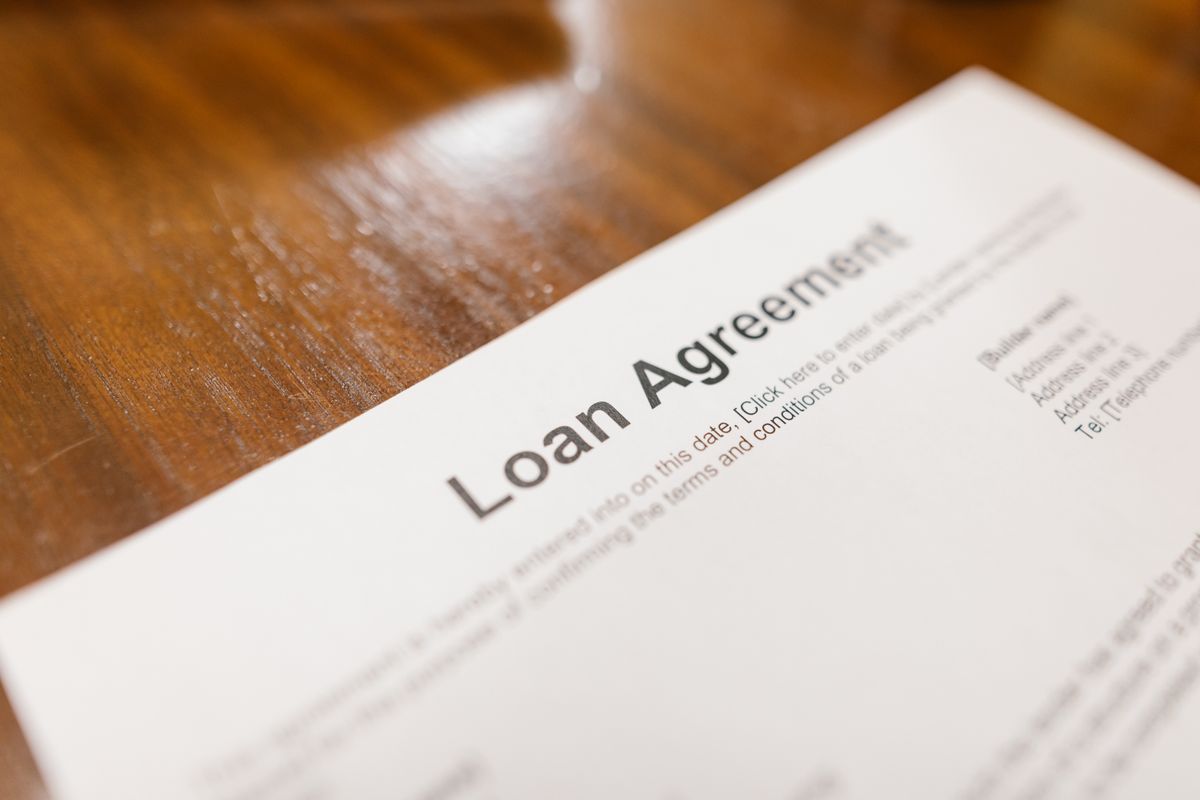 Close-up of a printed loan agreement on a wooden table, the document to read for APR, term and total of payments before signing water softener financing