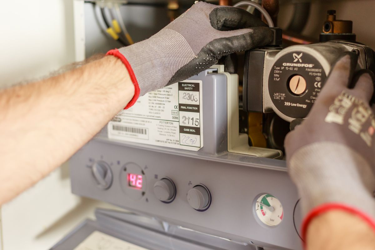 Hands adjusting a boiler system fitted with pressure instrumentation during a service flush