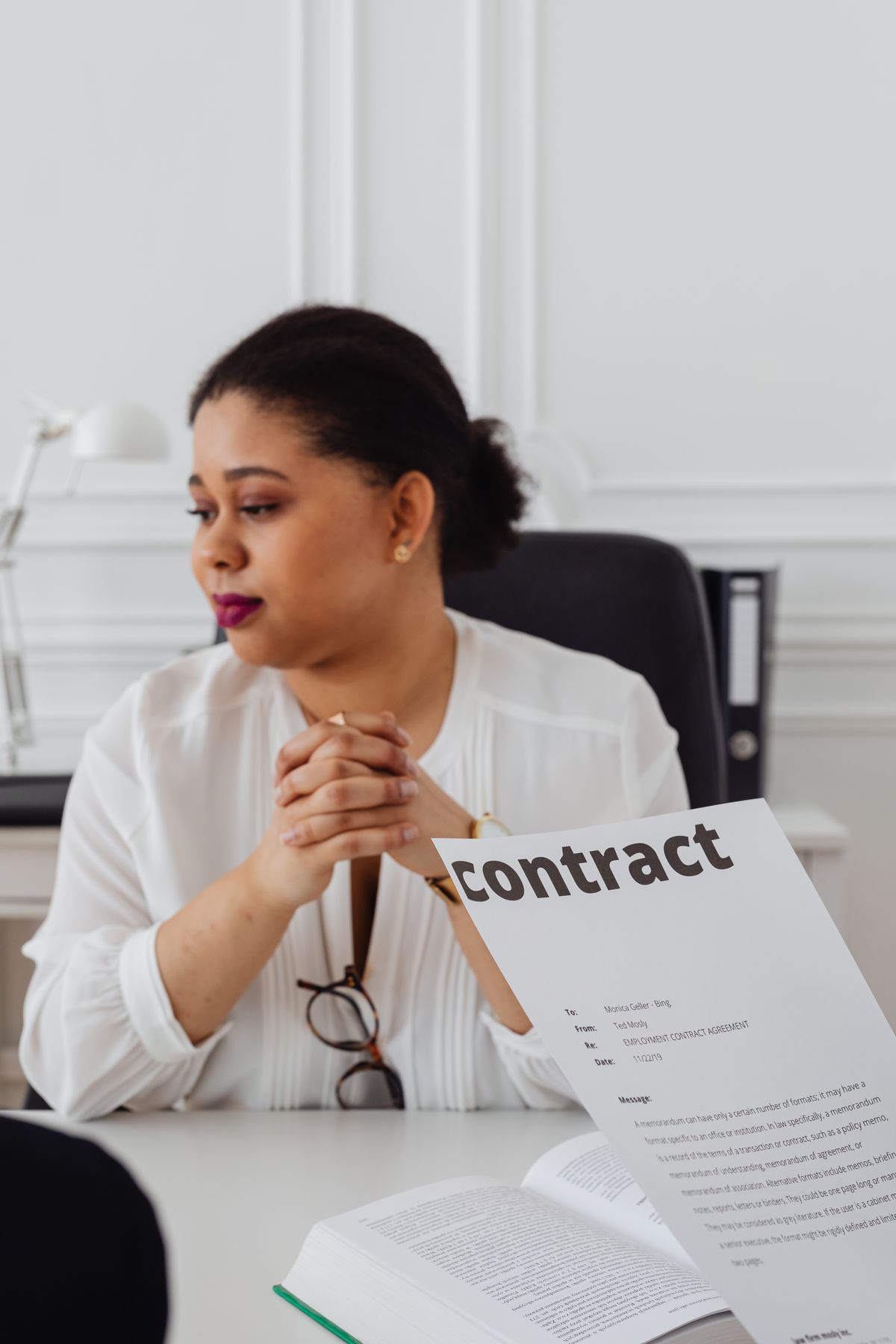 Woman at a desk with a printed contract in the foreground, the kind of fine print to compare when water softener warranties differ by component and brand
