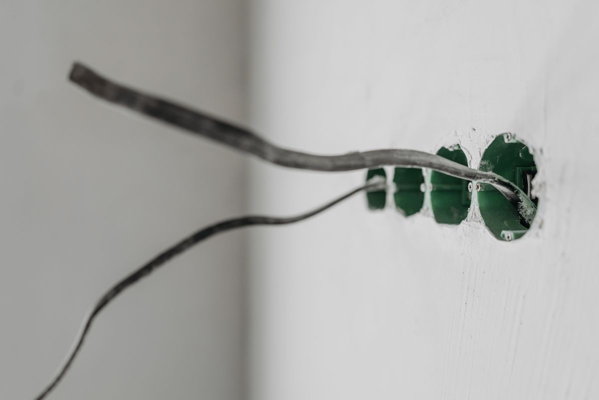 Electrical cable pulled through a row of new green wall boxes in an unfinished wall before the receptacles are fitted