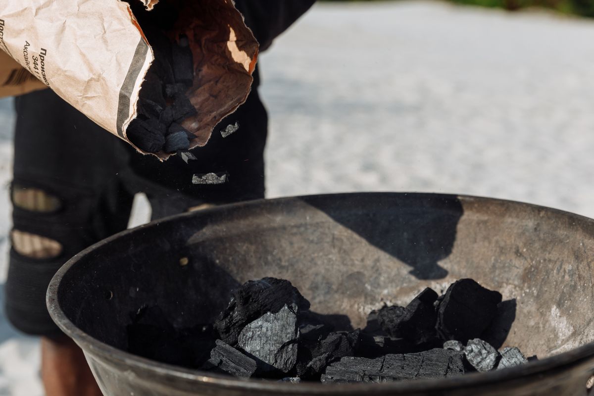 Charcoal being poured from a bag into a metal basin, the granular activated carbon media that removes chlorine before it reaches the resin