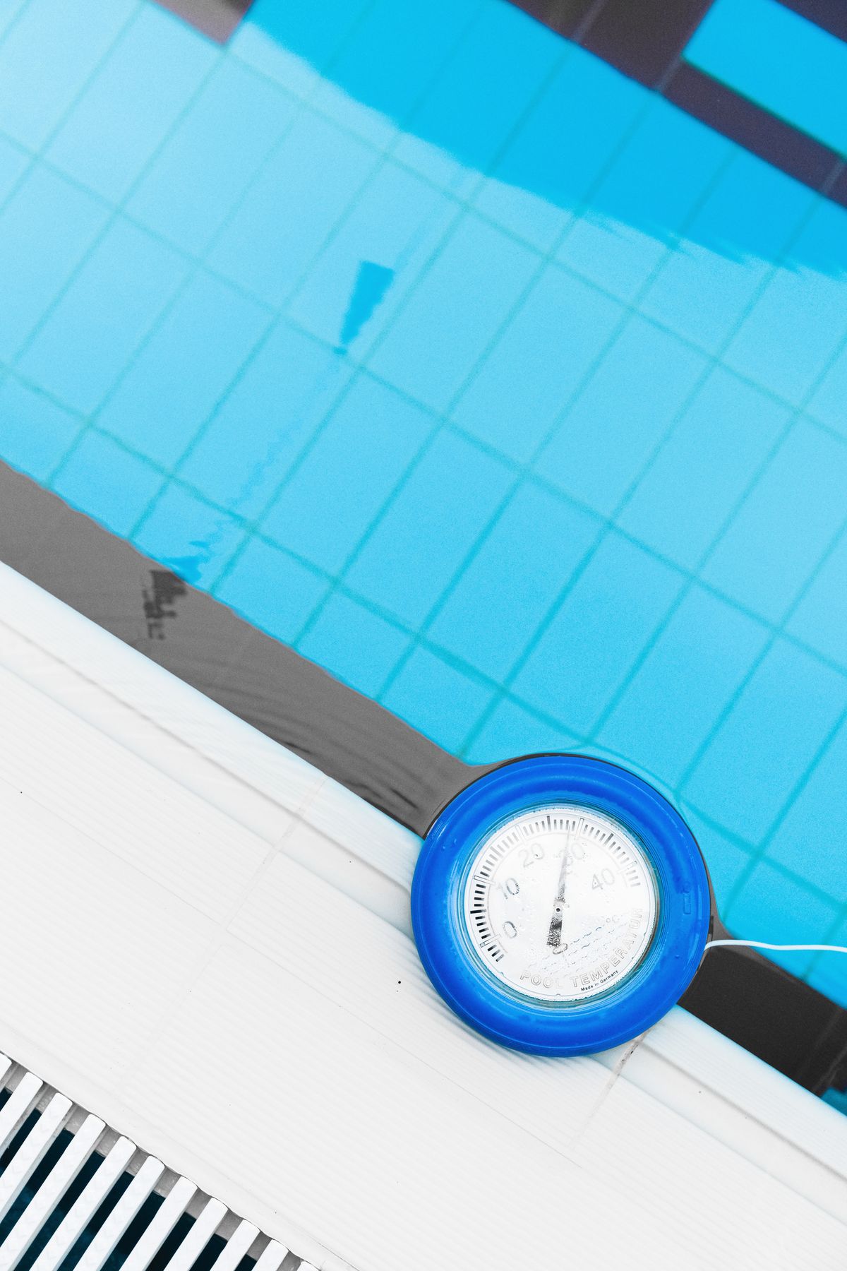 Thermometer measuring water temperature at a pool edge, a reference point for the chlorine smell people recognise