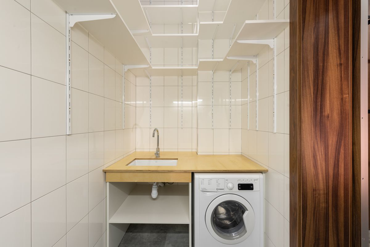Small laundry room with a washing machine beside a utility sink whose drain trap is visible underneath, a common place for a water softener to drain