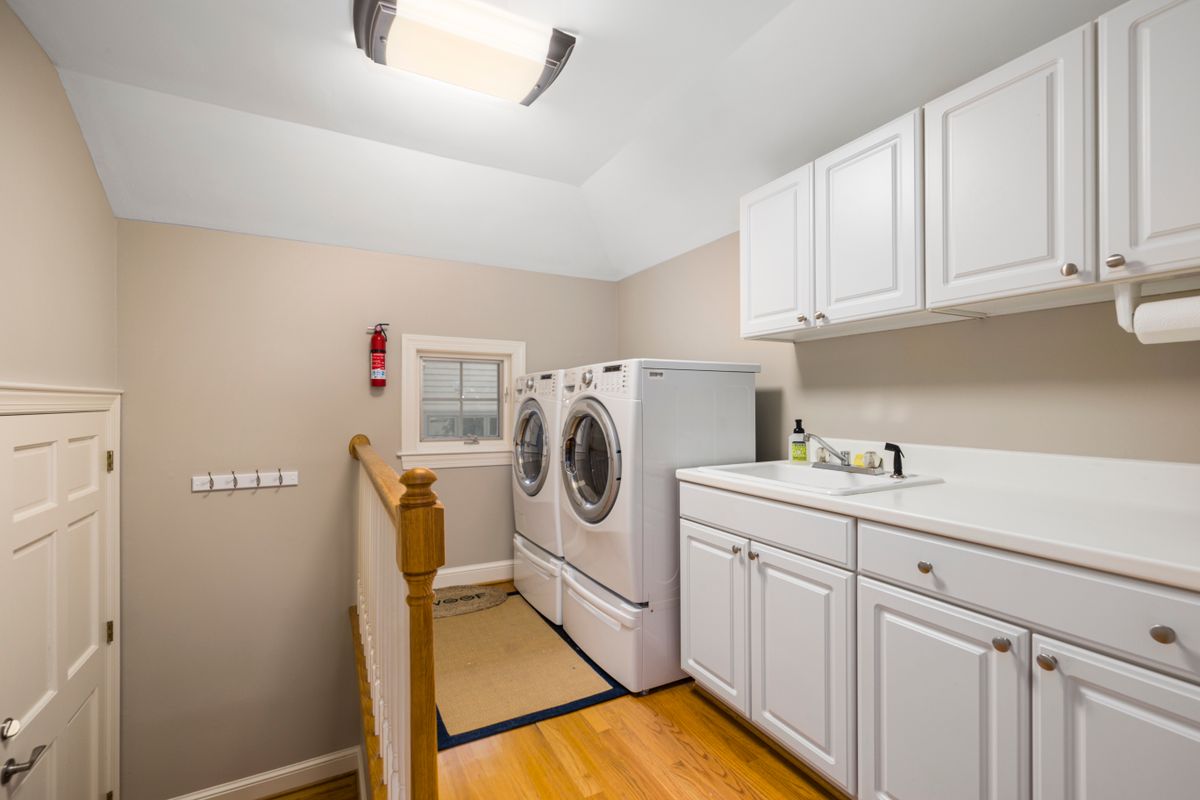 Home laundry room with a front-load washer and dryer, a sink and white cabinets, a tight utility space where a softener's tank layout has to fit