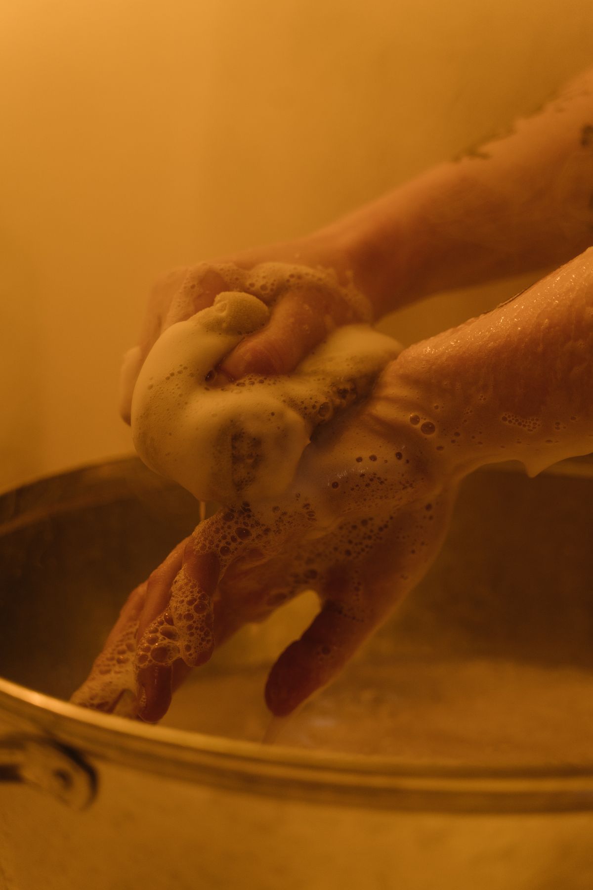 Close-up of hands lathered with soap, showing the rich lather soft water produces from a small amount of product