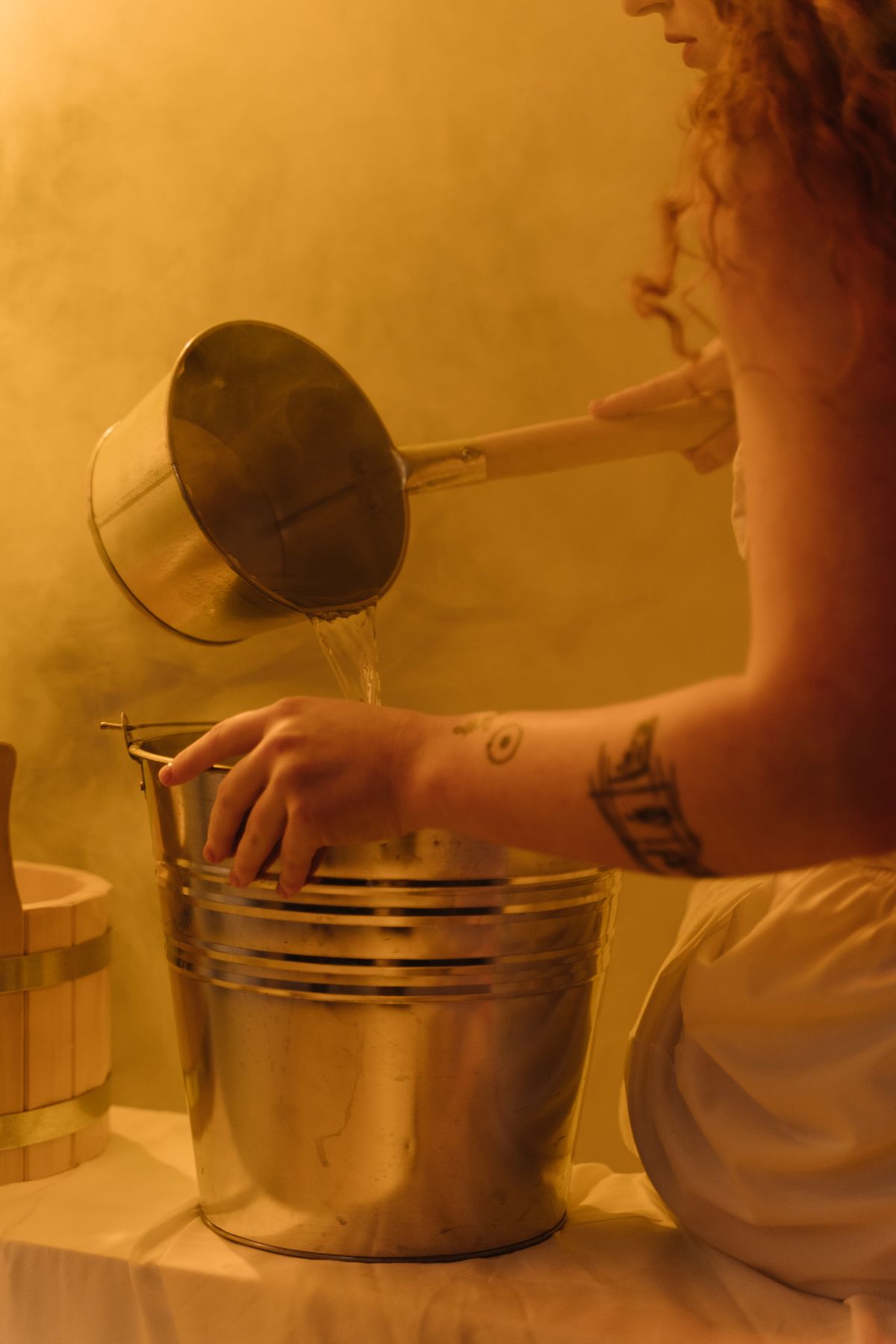 Woman filling a stainless steel bucket with water, the simple timed-fill measurement that establishes a softener backwash flow rate