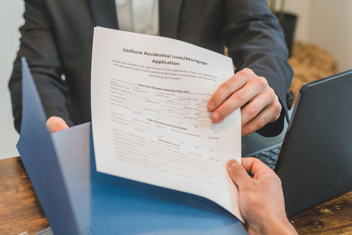 Loan application form being handed across a desk, the separate financing paperwork that comes with many in-home water softener sales
