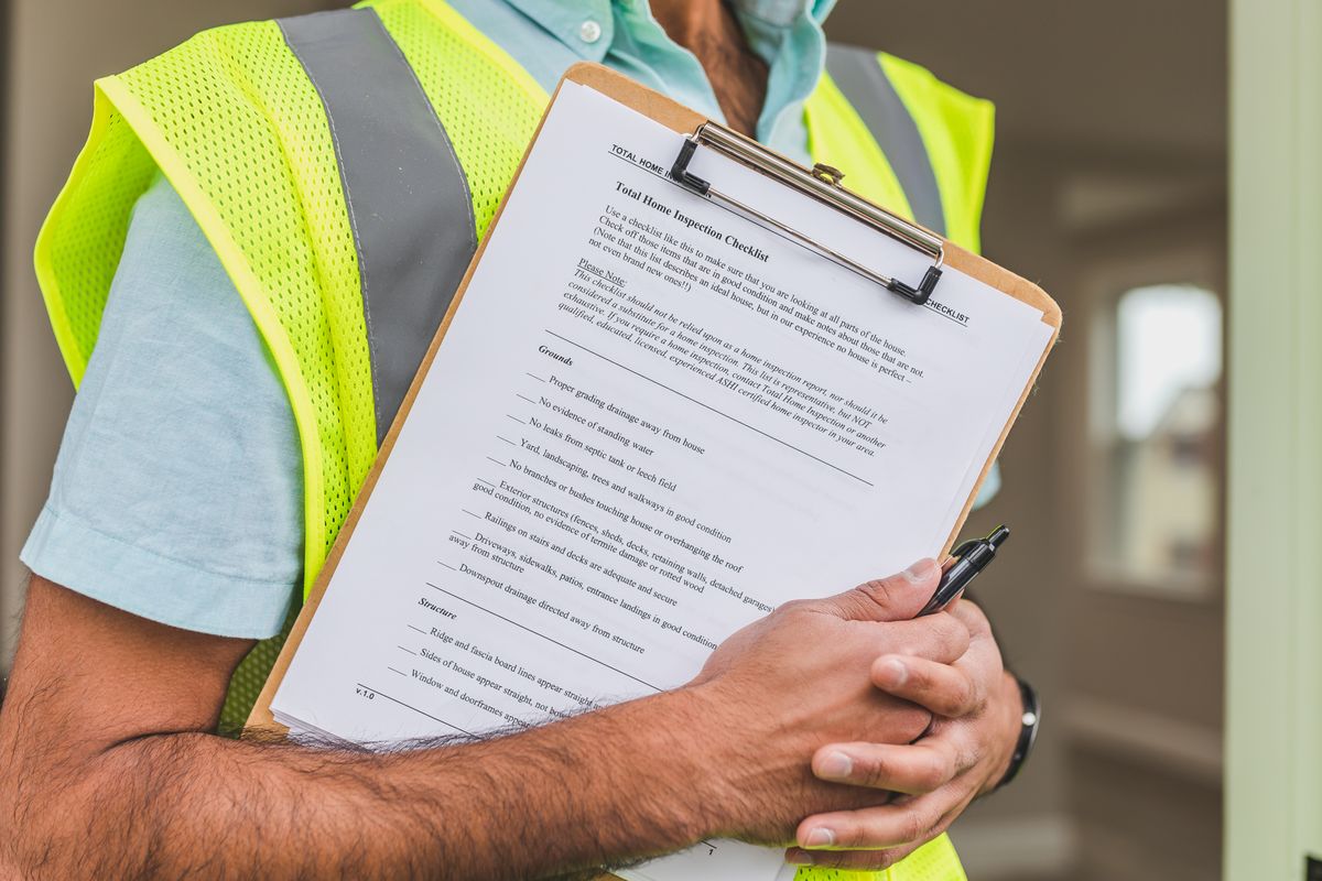 Person in a yellow reflective safety vest holding a checklist, the kind of structured triage that sorts softener faults into DIY and professional jobs
