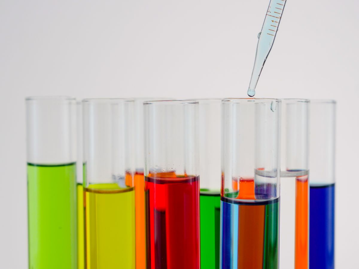 Row of test tubes holding graded colour solutions beside a pipette, the titration step that gives a hardness figure rather than a colour band