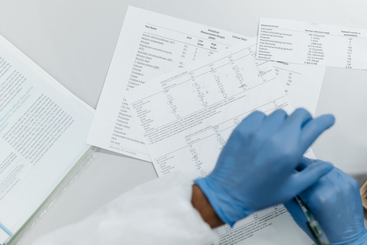 Gloved hands reviewing printed laboratory test results, the certified tannin and iron numbers that decide the treatment order