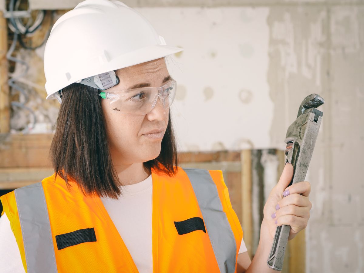 Person holding a large adjustable plumbing wrench, a tool that should stay off plastic softener valve caps, which are designed to be tightened by hand