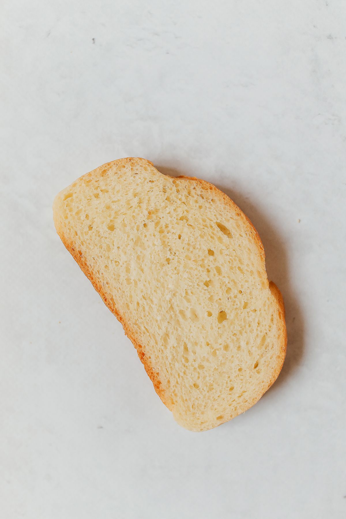 Single slice of white bread on a pale background, the everyday food used to compare sodium in softened water