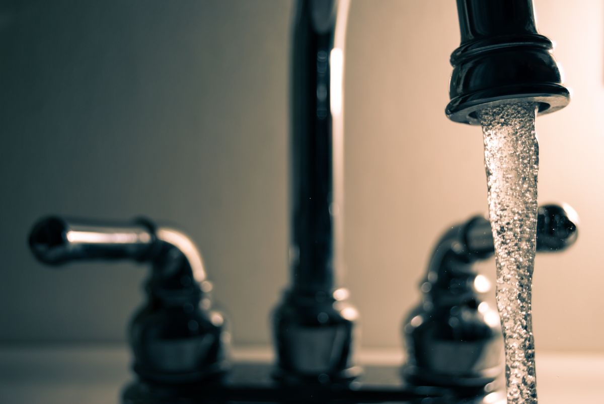 Water running from a stainless steel faucet, flushed before collecting a lab water sample