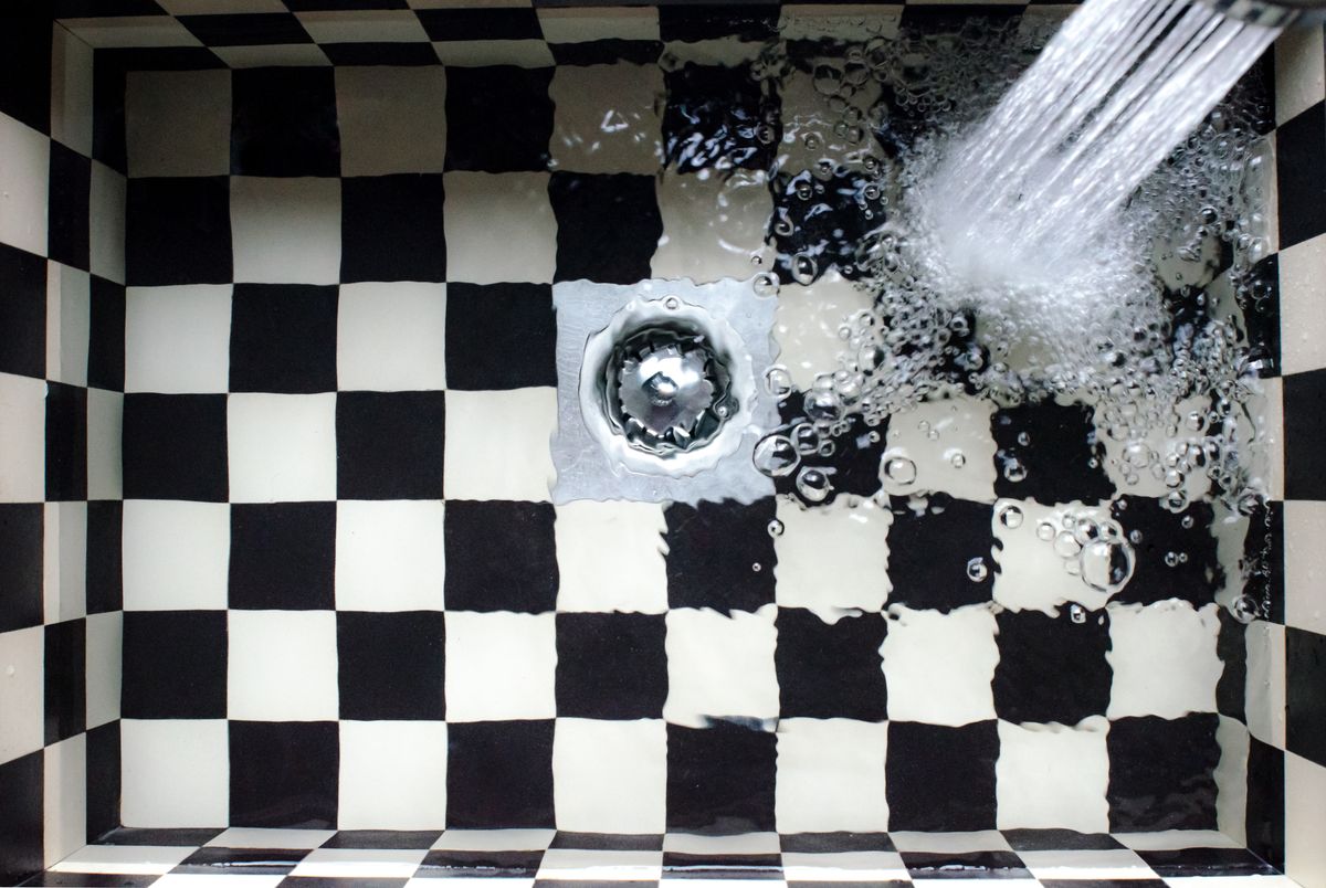 Water running into a black and white checkered sink and swirling toward the drain, where every gallon of softener regeneration water ends up