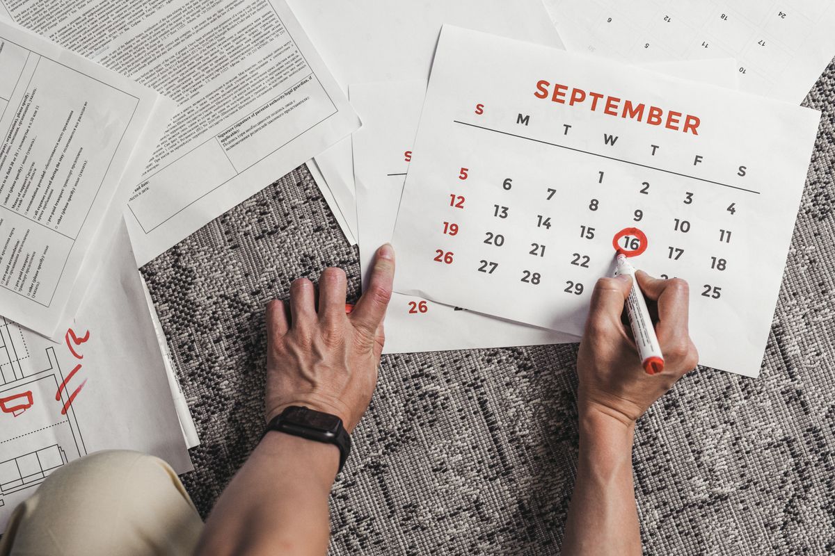 Hands circling a date on a September calendar beside printed household paperwork, tracking the monthly payment of a Culligan water softener rental