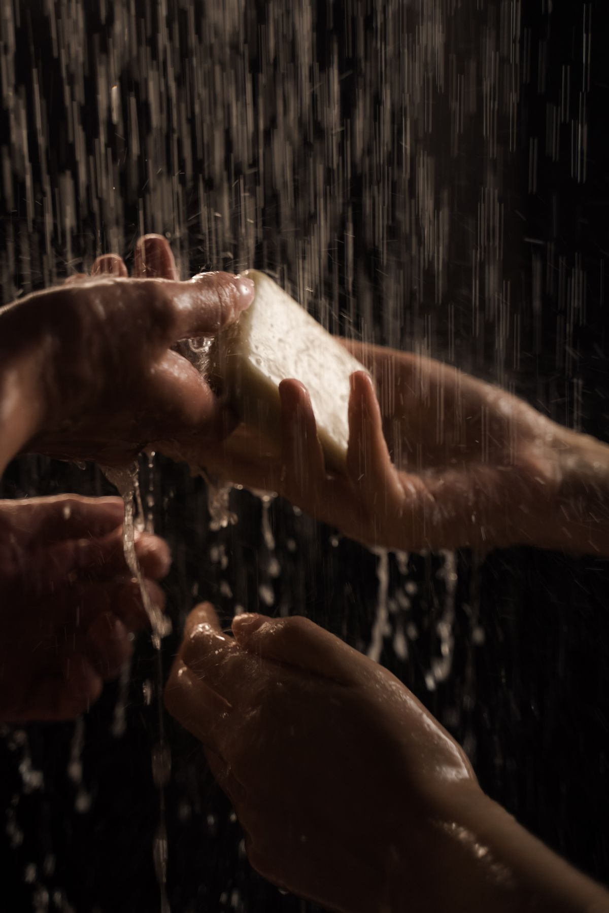 Hands lathering soap under running water, the step where soft water makes the usual dose a substantial overdose