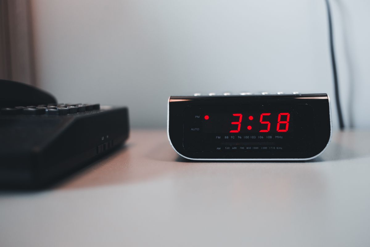 Digital alarm clock display showing the time on a white surface, a reminder that a softener's time-of-day and regeneration-time settings decide when it cycles