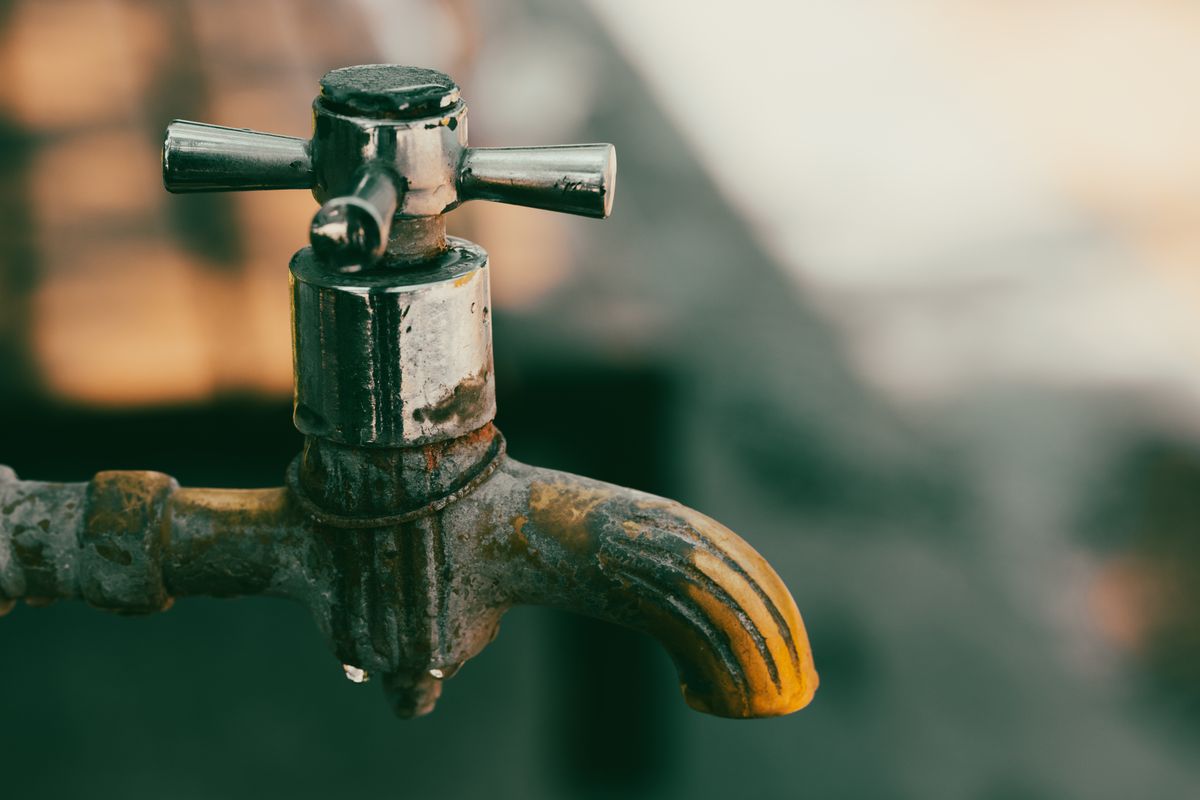 Corroded metal faucet with orange staining, one of the household problems mistaken for hard water