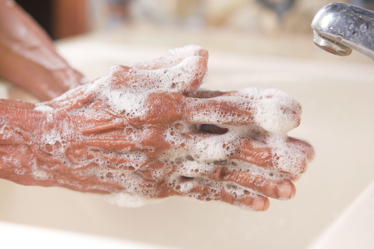 Hands covered in soap lather under a chrome tap, the soap behaviour a salt-free system does not change