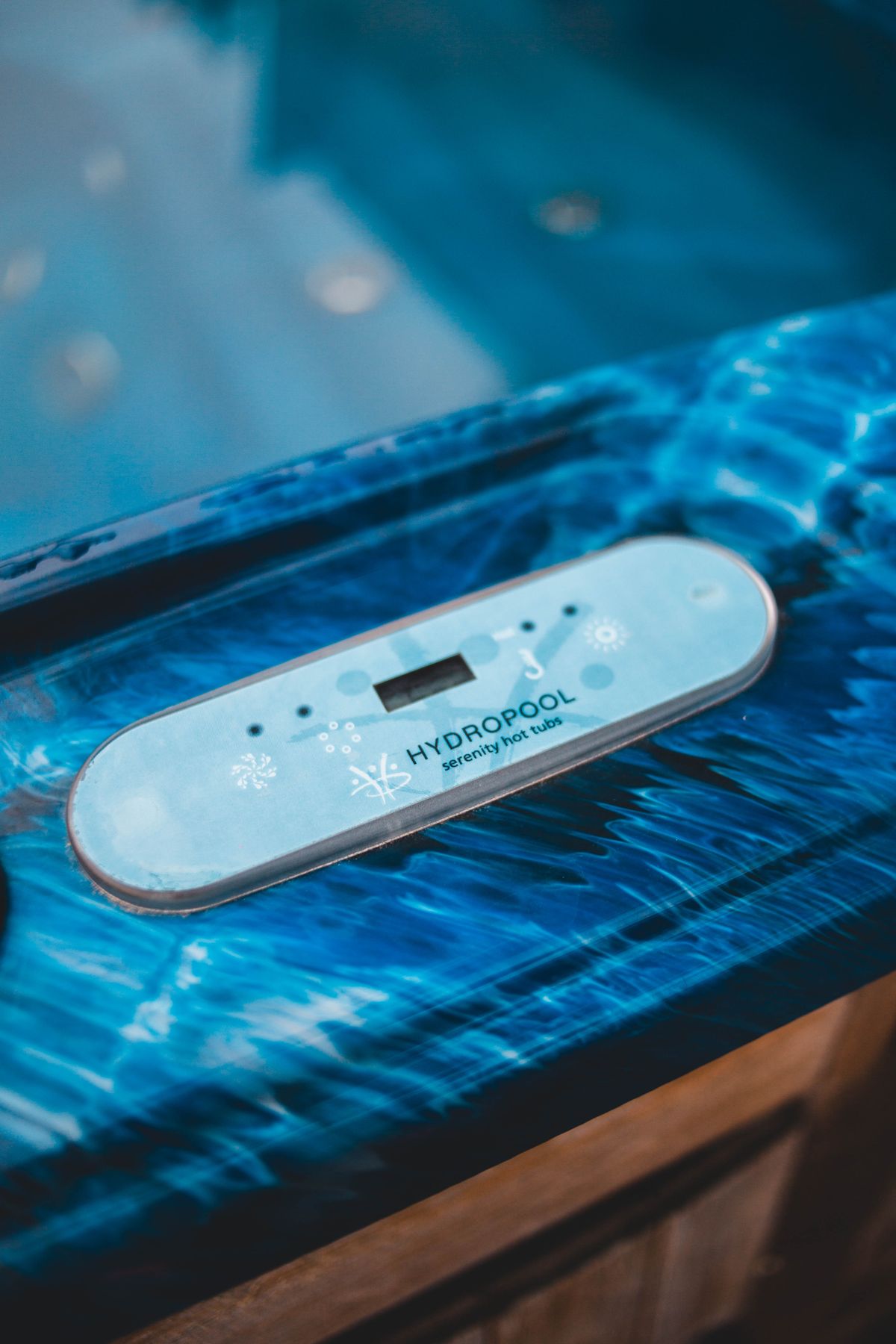 Hot tub control panel on the rim of an acrylic spa shell, with the heated water below