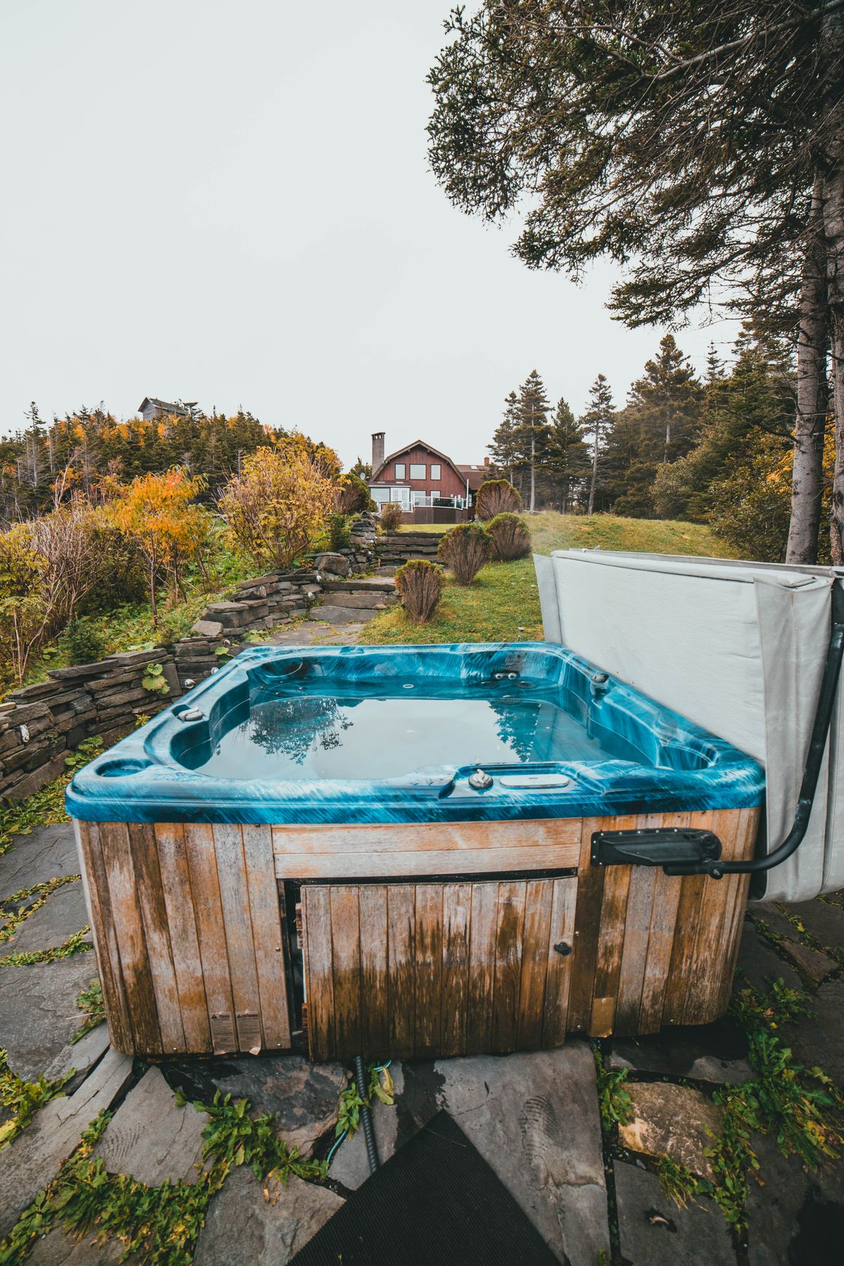 Outdoor acrylic hot tub with its cover folded back in a garden, filled with water whose calcium hardness needs balancing